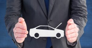 Two male hands protecting the image of a paper car. Where to place the vehicle tracker.